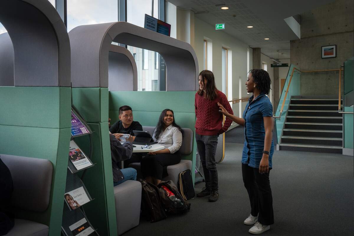 a group of students talking to each other inside the computer science building